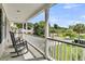 A covered porch features black rocking chairs and a scenic view of the street and a pond at 1436 Lagoon Park Cir, Mount Pleasant, SC 29466