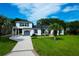 A beautifully landscaped two-story home with a white exterior, blue trim, a long driveway and mature trees at 1468 N Relyea Ave, Charleston, SC 29412