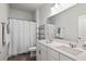 Bright bathroom with double sinks, white cabinets, and a shower with white curtain at 1682 Mermentau St, Mount Pleasant, SC 29466