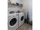 Clean laundry room featuring modern washer and dryer units, storage shelving, and tiled floors at 1682 Mermentau St, Mount Pleasant, SC 29466