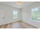 Well-lit bedroom with hardwood floors, neutral walls, and two windows offering natural light at 1685 Old Military Rd, Charleston, SC 29412