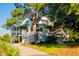 Stately two-story home with a gravel driveway and screened-in porch, surrounded by mature trees at 2312 Rushland Landing Rd, Johns Island, SC 29455