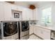 This laundry room has a washer and dryer with white cabinets, sink, and patterned flooring at 2312 Rushland Landing Rd, Johns Island, SC 29455