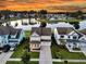 Stunning aerial view of a lakeside home with a landscaped yard and a two-car garage under a dramatic sunset sky at 292 Calm Water Way, Summerville, SC 29486