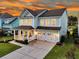 Elegant two-story home boasts a cozy front porch, double garage, and lush landscaping with a picturesque sunset backdrop at 292 Calm Water Way, Summerville, SC 29486