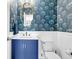 Stylish powder room featuring patterned wallpaper, vanity with blue cabinet, and white fixtures at 292 Calm Water Way, Summerville, SC 29486