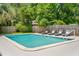 Relaxing poolside view with four lounge chairs, privacy fence, and lush landscaping at 43 Heathwood Dr, Charleston, SC 29407