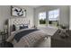 Serene bedroom showcasing tufted headboard, patterned bedding, neutral tones, and bright windows overlooking the neighborhood at 475 Caledon Ct, Johns Island, SC 29455