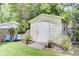 Charming backyard shed with a wooden ramp, surrounded by lush greenery, offering practical storage and appealing aesthetics at 5406 Dwight Dr, North Charleston, SC 29420