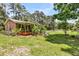 Backyard view featuring a covered patio, lush banana trees, and well-maintained lawn at 7274 Commodore Rd, Hollywood, SC 29449