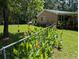 Backyard with brick home, grass lawn, and vibrant orange flowers bordering the fence at 7274 Commodore Rd, Hollywood, SC 29449