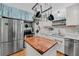 Clean kitchen with stainless steel appliances, white cabinets, butcher block island, and pendant pot rack at 7274 Commodore Rd, Hollywood, SC 29449