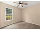 Cozy bedroom with neutral carpet, ceiling fan, and bright window with a green outdoor view at 8116 Long Shadow Ln, North Charleston, SC 29406