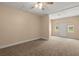 Carpeted bonus room with a ceiling fan, windows, and access to the attic and backyard at 8116 Long Shadow Ln, North Charleston, SC 29406