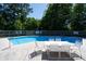 Community pool with a white table and chairs for relaxing by the water, surrounded by lush greenery at 8483 Yadkin Cir # D, North Charleston, SC 29406