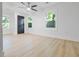 Spacious bedroom with light hardwood floors, ceiling fan, three windows, and modern black doors at 1129 Dickson Ave, Hanahan, SC 29410