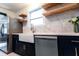 Renovated kitchen featuring navy cabinets, a farmhouse sink, light countertops, marble backsplash and wooden shelving at 1129 Dickson Ave, Hanahan, SC 29410