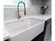 Close-up of the farmhouse sink with brass faucet, stone countertops and backsplash and stainless steel appliances at 1129 Dickson Ave, Hanahan, SC 29410