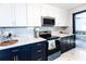 Bright kitchen with white and navy cabinets, stainless steel appliances, stone countertops, and open access to living room at 1129 Dickson Ave, Hanahan, SC 29410
