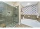 Well-lit bathroom featuring tiled glass shower and garden tub with decorative wallpaper at 125 Pier View St # 408, Charleston, SC 29492