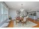 Dining room with chandelier, hardwood floors and shuttered windows open to modern kitchen at 125 Pier View St # 408, Charleston, SC 29492