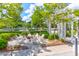 A pleasant outdoor social area with Adirondack chairs arranged around a fire pit, surrounded by lush landscaping at 1888 Nola Run, Summerville, SC 29485