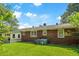 A brick home features a well-maintained backyard with mature trees, grass and central air conditioning unit at 1900 Morgan Ave, North Charleston, SC 29406