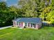 Brick house with a well-manicured lawn, a red front door, and a backdrop of lush trees at 214 E Edgefield Dr, Summerville, SC 29483