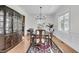 Elegant dining room with a large china cabinet, table set for six, a chandelier, and ample natural light from two windows at 3513 Flowering Oak Way, Mount Pleasant, SC 29466