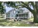 Charming home exterior with a screened porch, fire pit, lush green lawn, and beautiful large oak trees at 3513 Flowering Oak Way, Mount Pleasant, SC 29466