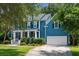Charming blue two-story home featuring a well-manicured lawn, a columned porch and an attached two-car garage at 3574 Toomer Kiln Cir, Mount Pleasant, SC 29466