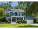 Charming blue two-story home featuring a well-manicured lawn, a columned porch and an attached two-car garage at 3574 Toomer Kiln Cir, Mount Pleasant, SC 29466