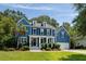 Charming blue two-story home featuring a well-manicured lawn, a columned porch and an attached two-car garage at 3574 Toomer Kiln Cir, Mount Pleasant, SC 29466