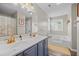 Bright bathroom with double sinks, blue vanity, and a soaking tub with a window at 3810 Marshfield Rd, Johns Island, SC 29455