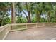 Wooden deck with white railings overlooking a lush backyard filled with mature trees and palm trees at 40 Greensward Rd, Kiawah Island, SC 29455