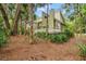 Exterior back home view showing patio, green siding and roof, and wooded perimeter at 40 Greensward Rd, Kiawah Island, SC 29455