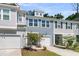 View of the townhome with a white garage door, manicured lawn, and a small tree in the front yard at 493 Trotters Ln, Moncks Corner, SC 29461