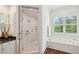 Elegant bathroom with marble walk-in shower, soaking tub, white cabinets, and natural light from a window at 510 Traders Aly, Mount Pleasant, SC 29464
