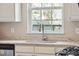 Bright kitchen featuring granite countertops, stainless steel faucet, and white cabinets beneath a large window at 518 Cecilia Cove Dr, Charleston, SC 29412
