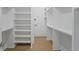 Bright, open walk-in closet with white custom shelving and wood flooring at 5710 Barbary Coast Rd, Hollywood, SC 29449