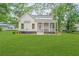 Exterior rear view of a charming white home featuring a spacious backyard and screened porch at 5710 Barbary Coast Rd, Hollywood, SC 29449