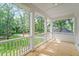 Inviting front porch with white columns and a wood floor overlooking a landscaped yard at 5710 Barbary Coast Rd, Hollywood, SC 29449