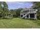 Home exterior showcases the lush lawn, trees and the elevated structure with screened porch and stairs at 633 Stono Edge Dr, Charleston, SC 29412