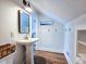 Bright bathroom featuring a pedestal sink, modern fixtures, and white walls with wood-look flooring at 837 Club Cottage Rd, Edisto Island, SC 29438