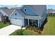Charming blue home showcasing a well-manicured lawn, covered porch, and attached two-car garage at 123 Leeward Lndg, Summerville, SC 29486