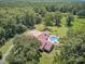 Aerial view shows a home with a pool, a basketball court, and a long driveway surrounded by trees at 138 Brant Acres Ln, Bonneau, SC 29431