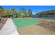 Full basketball court featuring bright green surface with red accents, surrounded by lush landscaping and secure fencing at 1636 Rivertowne Country Club Dr, Mount Pleasant, SC 29466