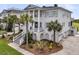Elegant two-story home featuring a lush front yard, mature palm trees, and a classic exterior at 1636 Rivertowne Country Club Dr, Mount Pleasant, SC 29466