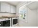 Bright laundry room with modern washer and dryer, storage cabinets, and a window at 1713 Banning St, Mount Pleasant, SC 29466