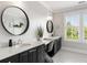 Modern bathroom featuring a double vanity with black cabinetry, round mirrors, and stylish black and white patterned floors at 1878 Headquarters Plantation Dr, Johns Island, SC 29455